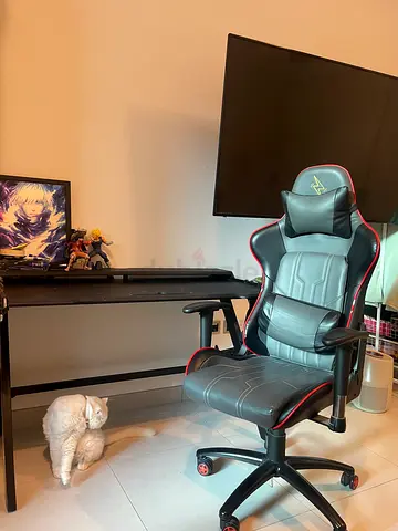 Comfortable black/red gaming chair and table with adjustable armrests and lumbar support.