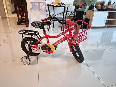 Red childrens bike with one training wheel and front basket - good condition