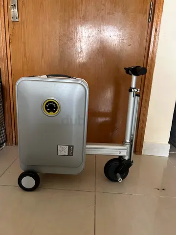 Small silver rolling suitcase with detachable scooter attachment
