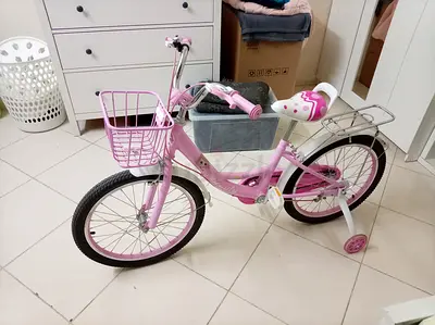 Lightly used pink childrens bicycle with training wheels and basket