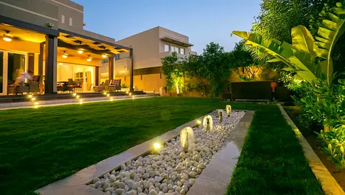 Well-kept private garden lawn with decorative pebble water feature and lighting