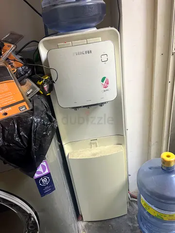 Used standing water cooler dispenser with empty bottles