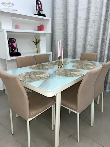 Modern glass-top dining table with 6 beige upholstered chairs