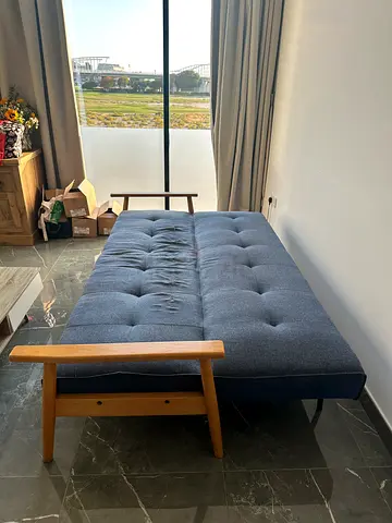 Convertible sofa bed — blue fabric with wooden arms, good condition