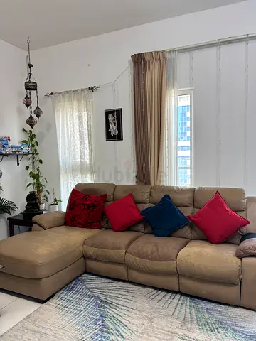 L-shaped beige leather sofa with chaise and cushions and reclines