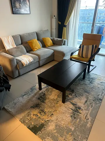 Light grey L-shaped sofa with armchair and modern area rug and coffee table - good condition