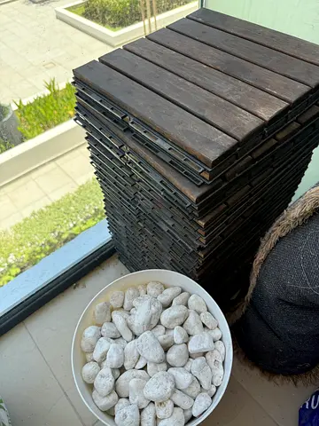 Stack of Interlocking Wooden Decking Tiles + Artificial White Rocks