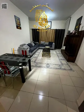 Furnished one-bedroom apartment with a balcony, open view, and free parking in Ajman.