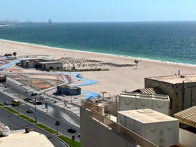 Two-bedroom apartment with a living room, direct sea view of Ajman Corniche. The apartment is fully lit and spacious.