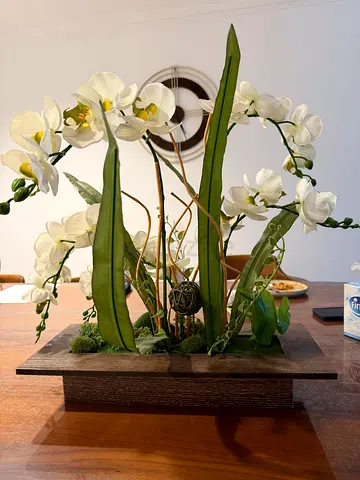 Decorative white orchid arrangement on wooden table base vase