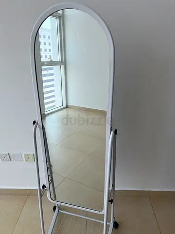 Full-length free-standing oval mirror with white metal frame and rack