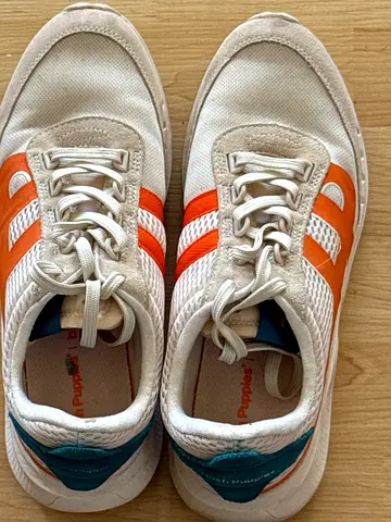 White casual sneakers with orange stripes, size not specified