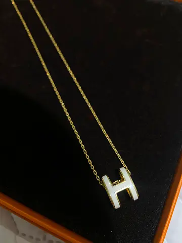 Gold-tone H pendant necklace with white enamel charm