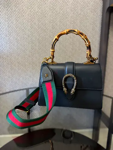 Black leather handbag with bamboo top handle and green-red strap