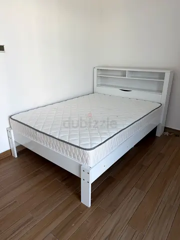 White wooden double bed frame with headboard shelving and mattress