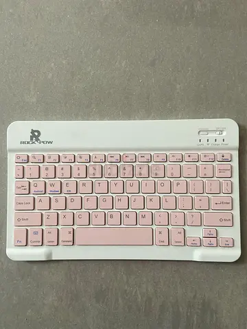 The Rock Pow wireless Bluetooth keyboard in white with pink keys. Its ultra-thin and portab