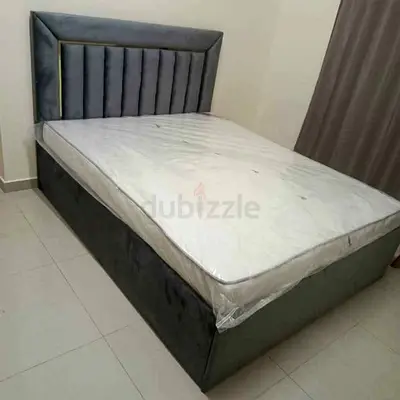 Grey upholstered double bed with storage and mattress -