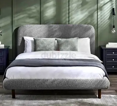 Grey upholstered double bed with rounded headboard