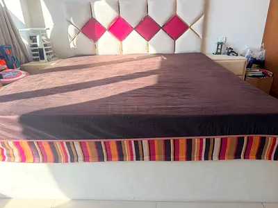 Queen-sized upholstered bed with padded headboard with mattress and two bedside tables.