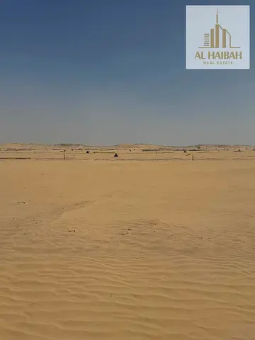 Two adjacent residential plots for sale, one corner plot and one regular plot, on a 97-meter main road in Sharjah - Al Sahma, near the entrance to Kho