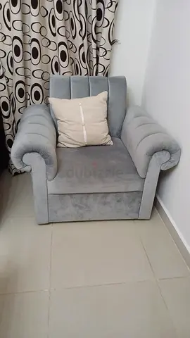 Single grey velvet armchair with rolled arms and cushion