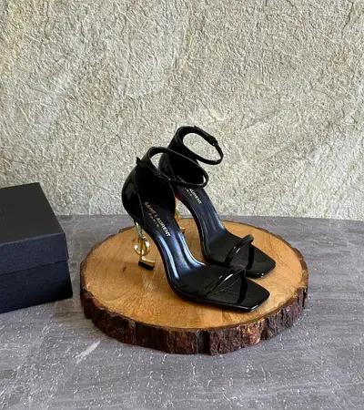 Black patent Saint Laurent-style ankle strap heels with gold sculpted heel