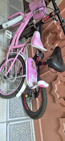 Pink childrens bicycle with training wheels and basket
