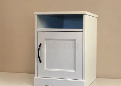 Small white bedside cabinet with storage shelf and door