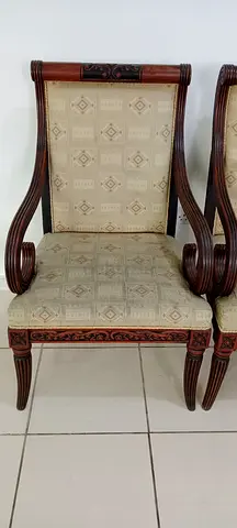 Pair of carved wooden dining chairs with patterned upholstery plus table