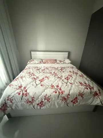 Queen-size bed frame with mattress and floral bedding