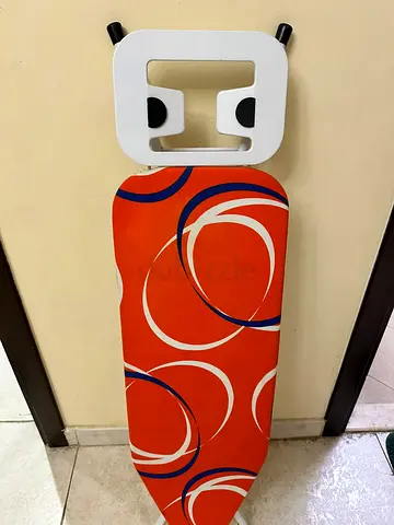 Used ironing board with colorful cover and wall mount holder