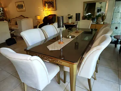 Elegant wooden and Glass Top Dining Table Gold Trim with 8 chairs. Purchase price 5000.