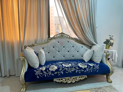 Antique-style carved wooden sofa with tufted back and blue seat cover