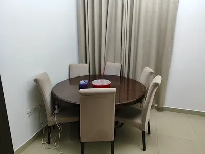 Round wooden dining table with 6 beige upholstered chairs - good condition