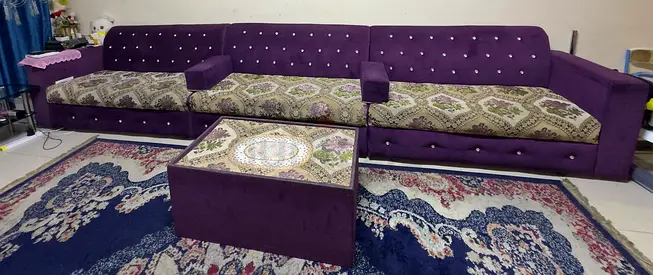 Long purple fabric sectional sofa with patterned cushions and matching ottoman