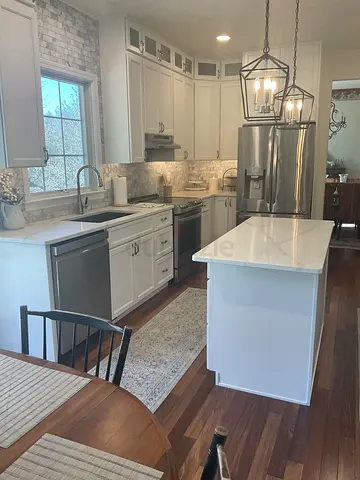 Modern White Kitchen with Island, Stainless Steel Appliances  Pendant Lights
