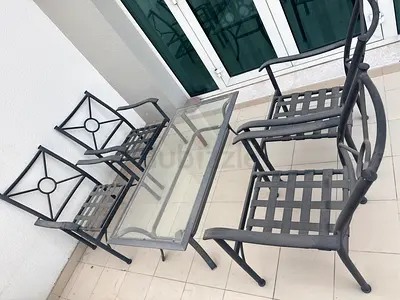 Outdoor glass-top dining table with four metal chairs - good condition