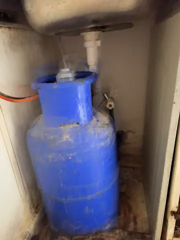 Blue portable gas cylinder under sink - used