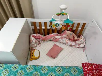 White wooden baby crib with mobile and mattress - sparsely used