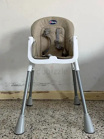 Compact beige baby high chair with safety harness