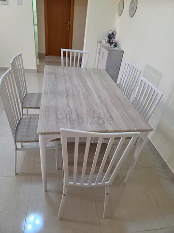 Light wood dining table with 6 white slat-back chairs
