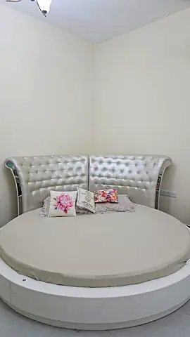 Round king-size bed with tufted silver headboard, a huge cupboard, dressing table and 2 side tables
