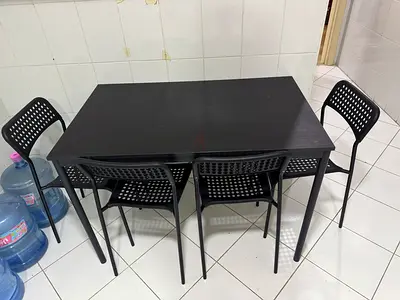 Black dining table with 4 matching plastic chairs - sturdy and compact