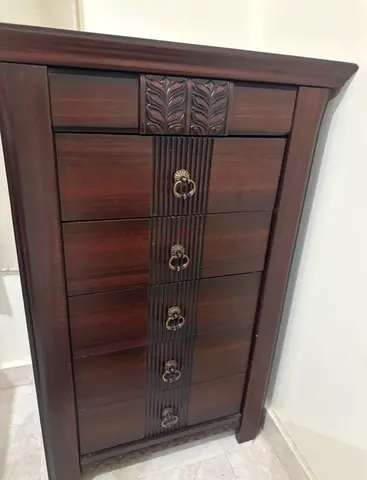 Tall dark wood chest of drawers with carved details
