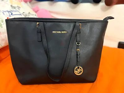 Michael Kors Jet Set tote features a distinctive circular MK logo charm