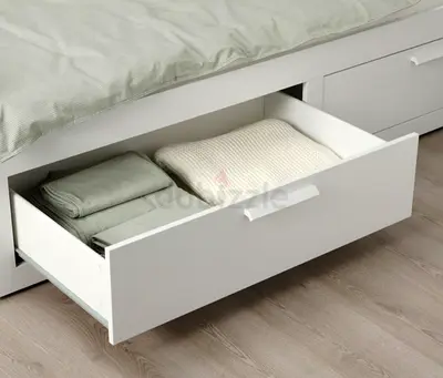 White platform storage bed with modern headboard - good condition from ikea with two mattresses .