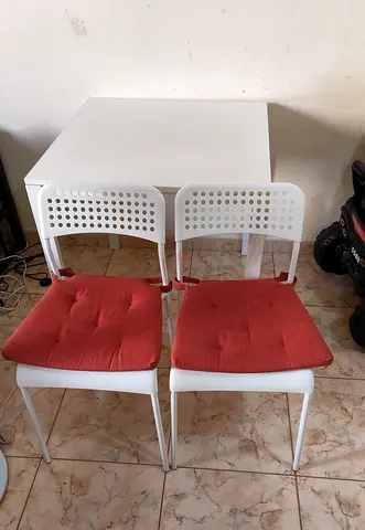 White dining table with 2 white chairs and red seat cushions - compact set