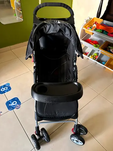 Well-kept black baby stroller with child tray and storage basket