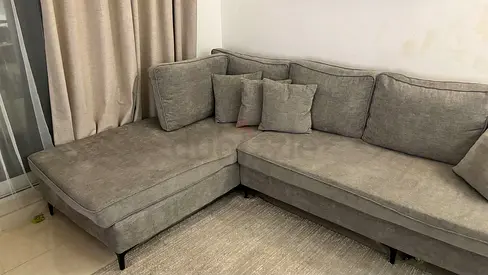 Light grey L-shaped fabric sofa with chaise — good condition.        Size: 3m x 1.95m x 0.9 m