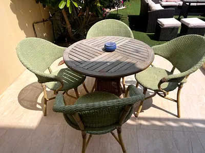 Outdoor rattan round dining table with 4 green woven chairs - good condition